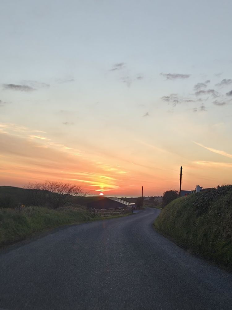 An empty road running to the coast at sunset