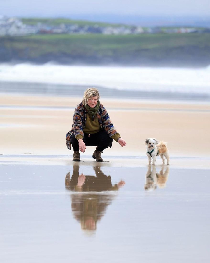 Cat walking her dog on wet sand at low tide